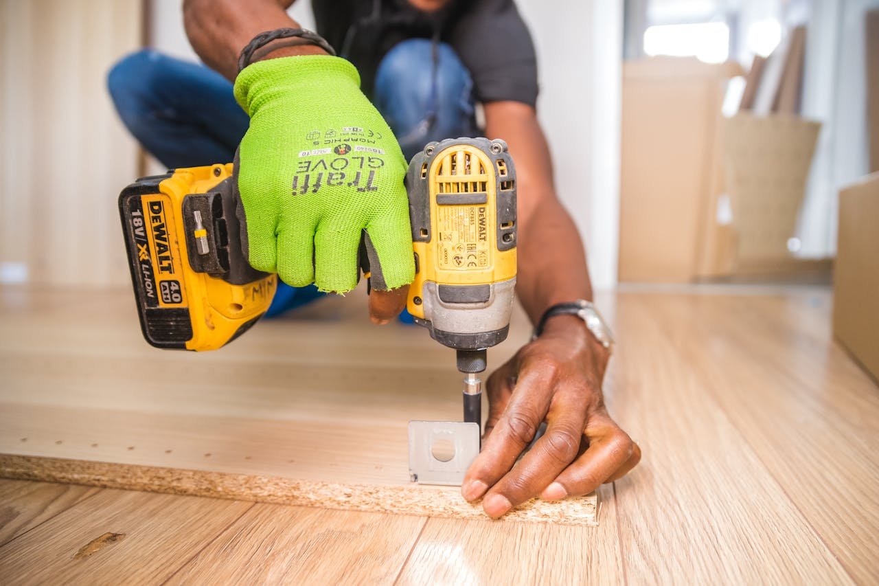 Nos Services Man using a power drill for home improvement on a wooden floor with precision.